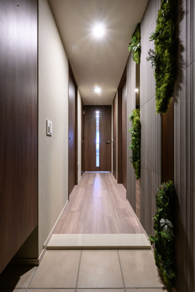 木目の建具と装飾グリーンを配した、落ち着いた雰囲気の廊下。